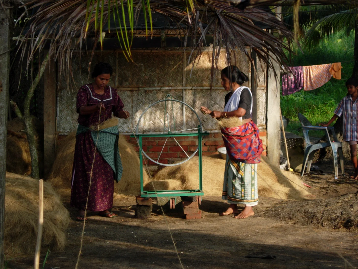 Women using a spinning wheel to make coir in Kollam
